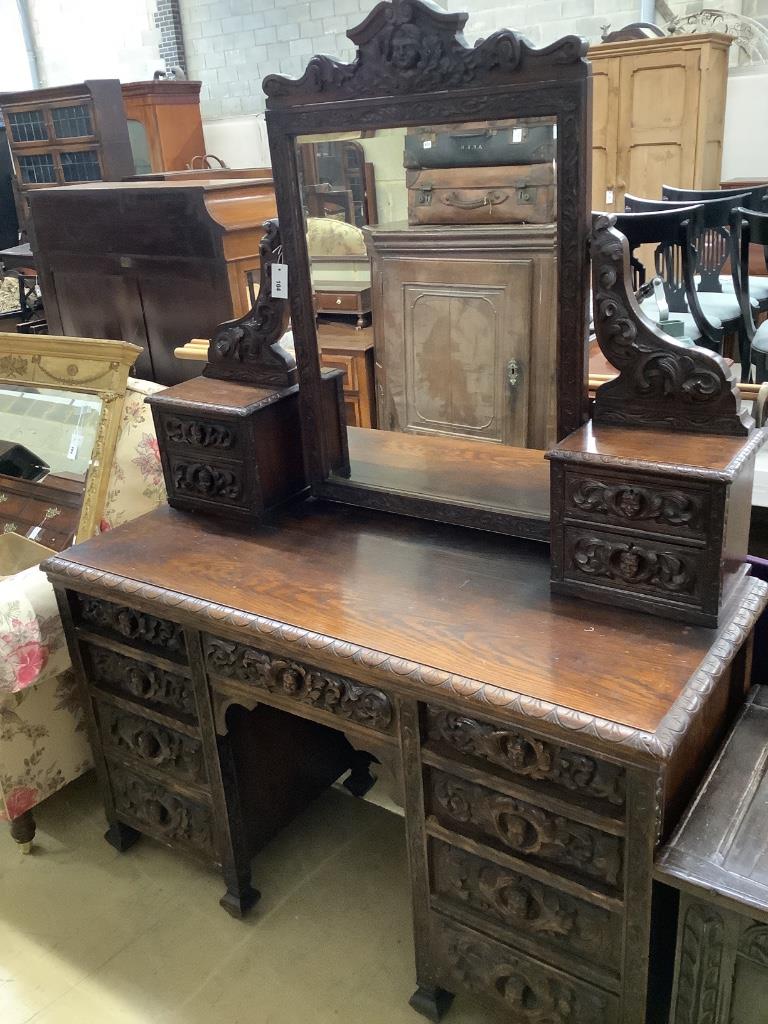 A late 19th century Flemish carveed oak kneehole dressing table, width 136cm depth 56cm height 183cm